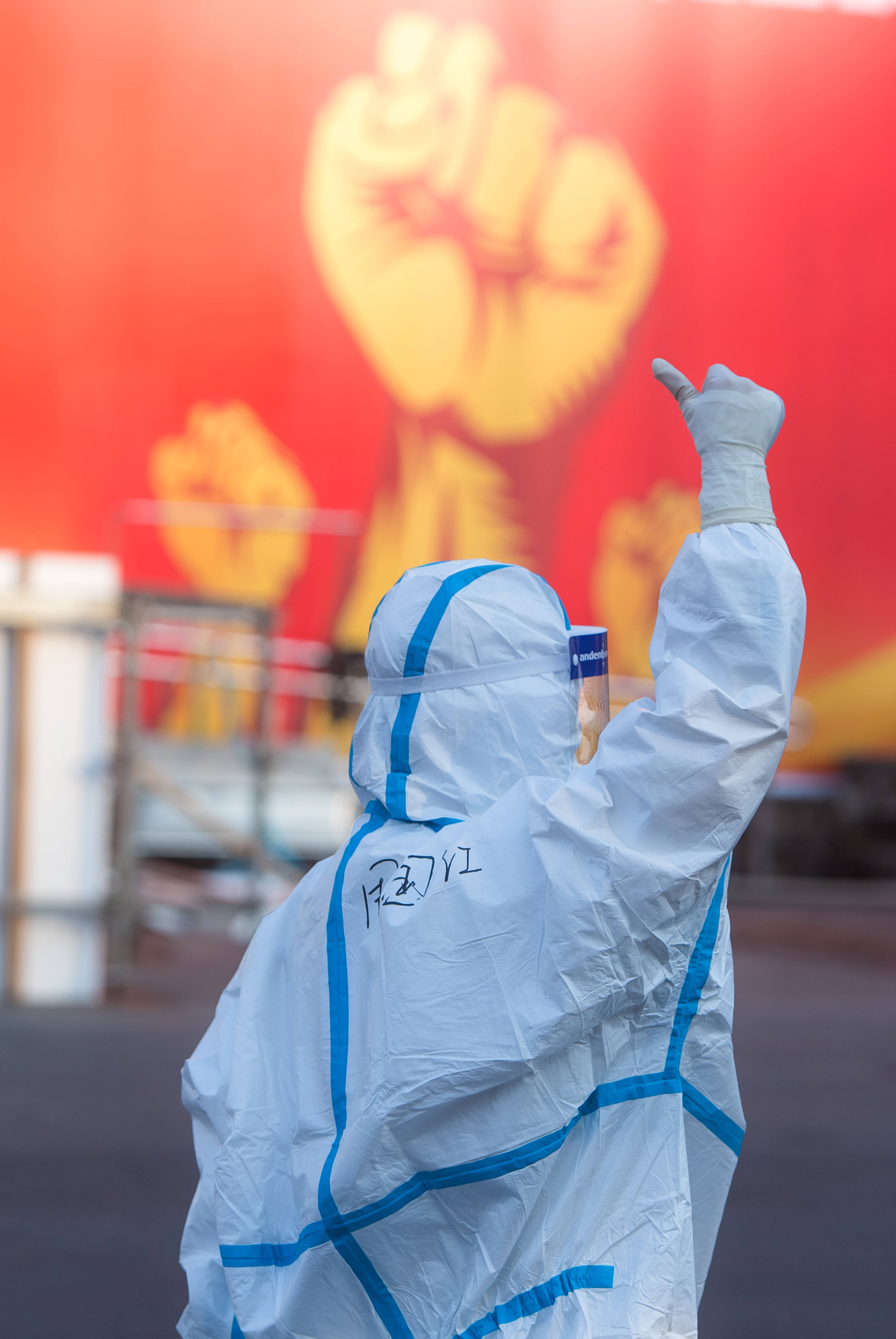 医务人员在湖北省武汉体育中心方舱医院前竖起拇指为自己和同伴加油