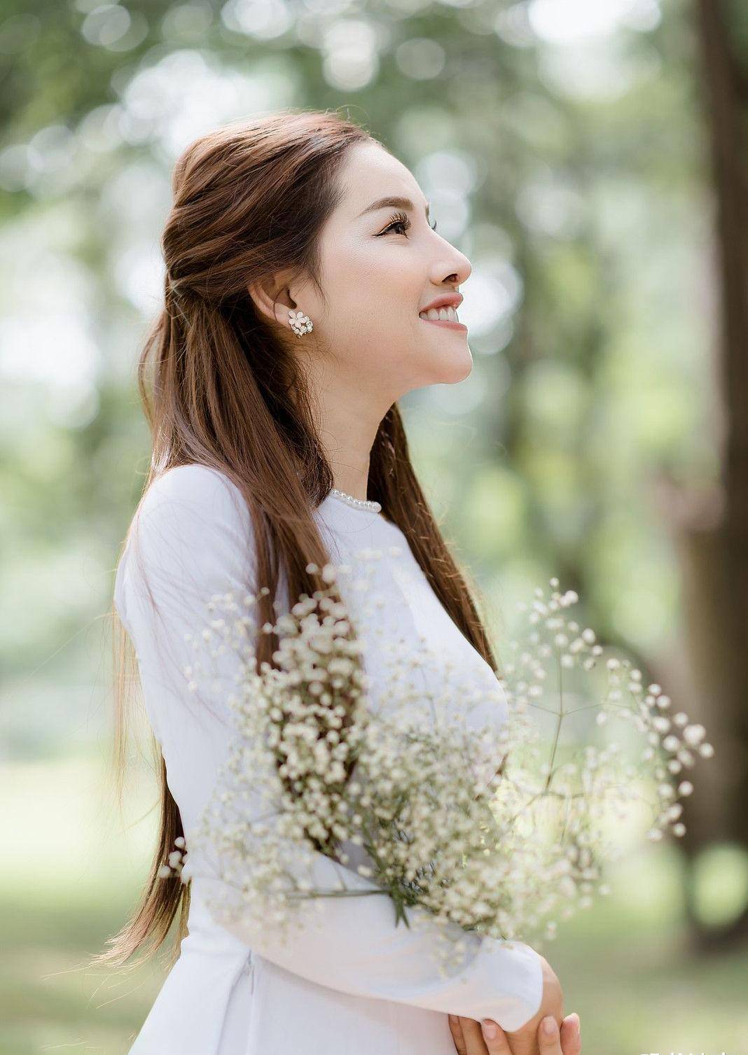 手捧鲜花,身穿白色奥黛,气质温婉,笑容阳光的国外姑娘