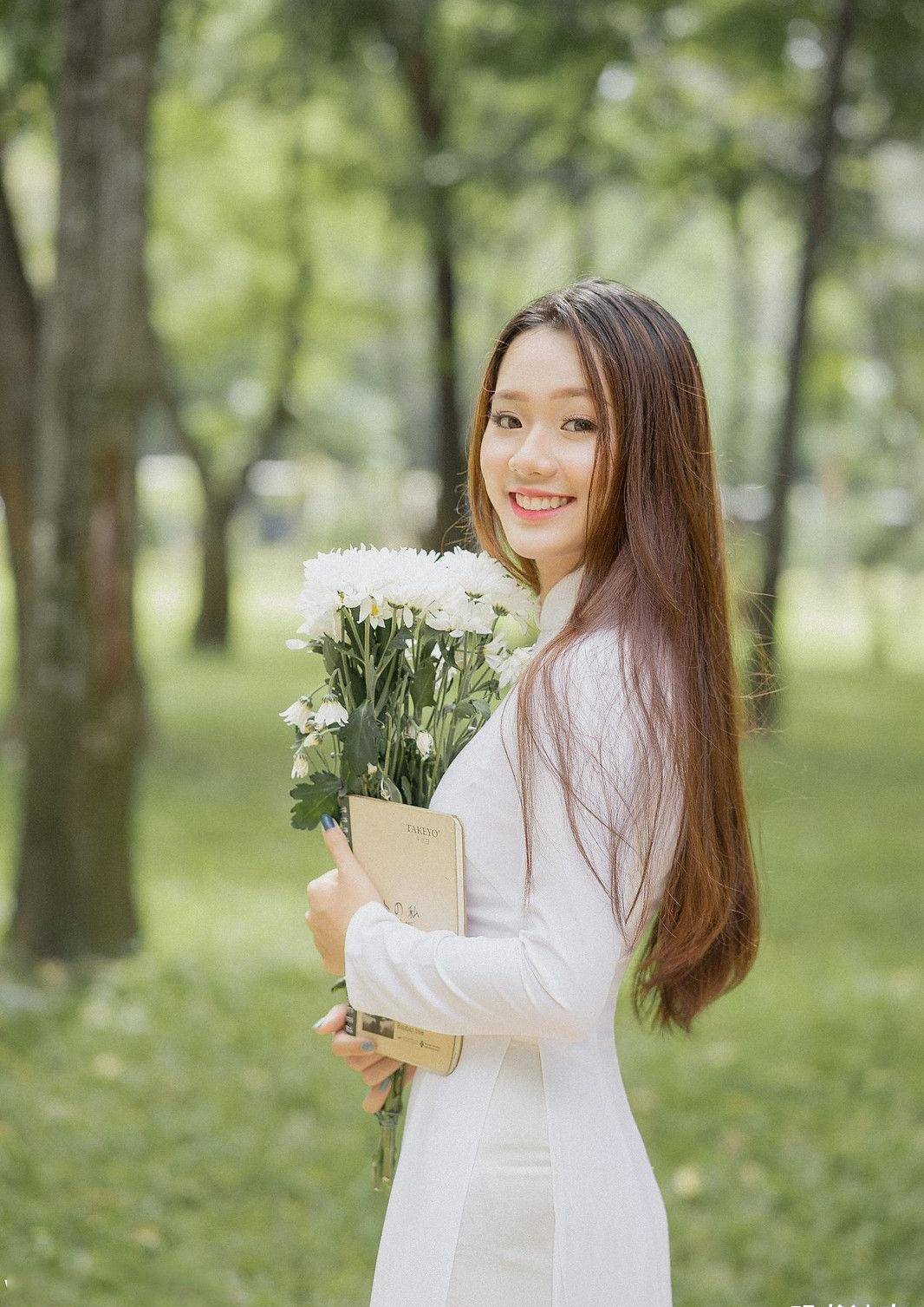 手捧鲜花,身穿白色奥黛,气质温婉,笑容阳光的国外姑娘真美_一笑_美女