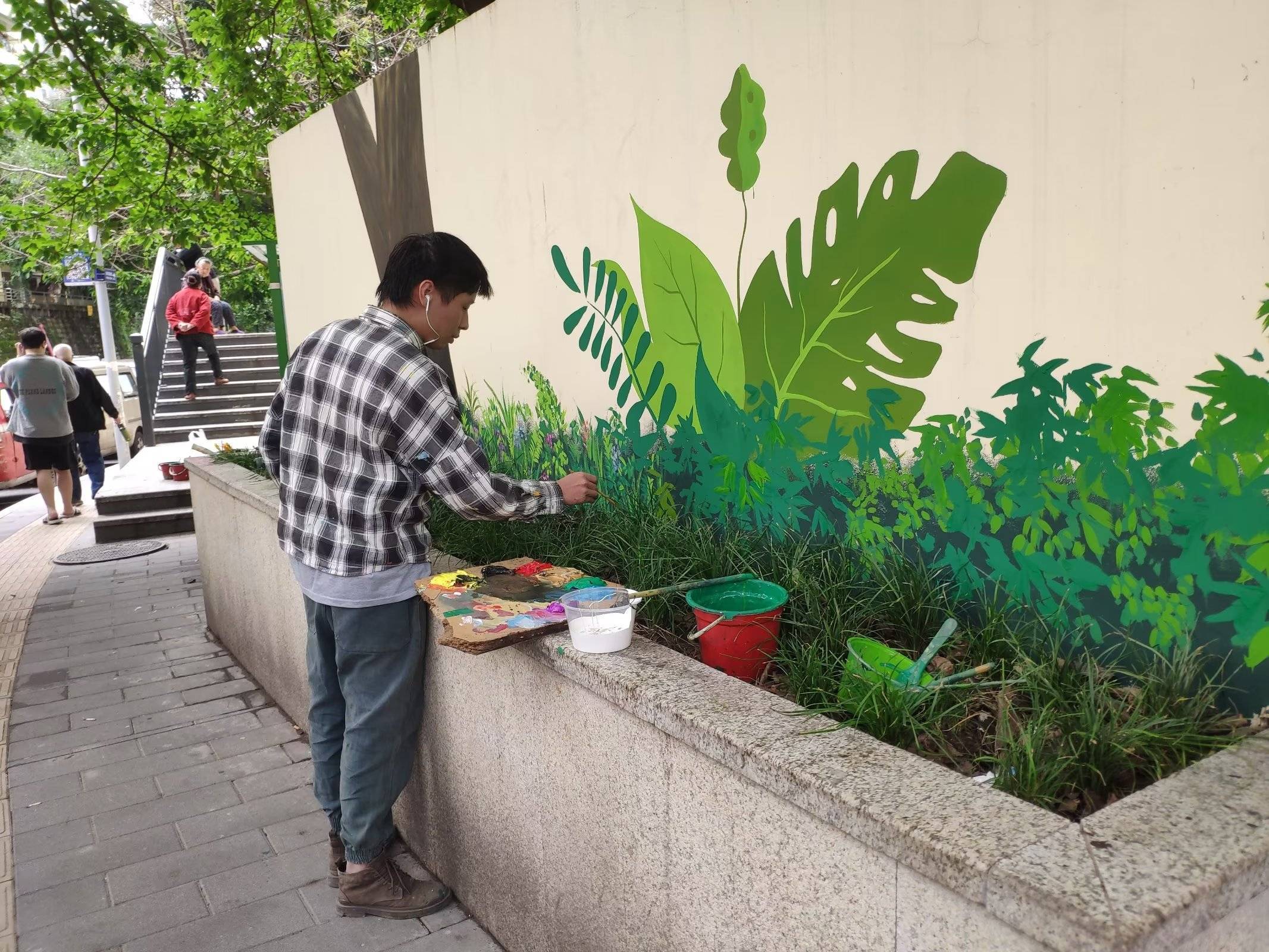 重庆:大学生街头创作墙体彩绘,蓝天白云花草树与绘画巧妙结合