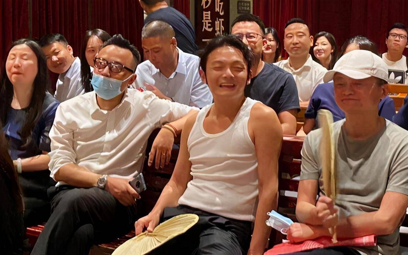 图上中间这位穿着跨栏背心,大裤衩子,脚上蹬着一双人字拖的年轻人就是