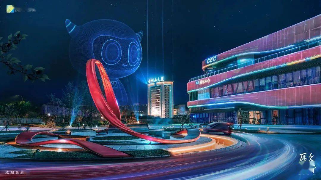 夜景中，一座现代化建筑前有巨大卡通形象气球和红色雕塑，车辆留下的光轨环绕，呈现出繁忙都市的活力。