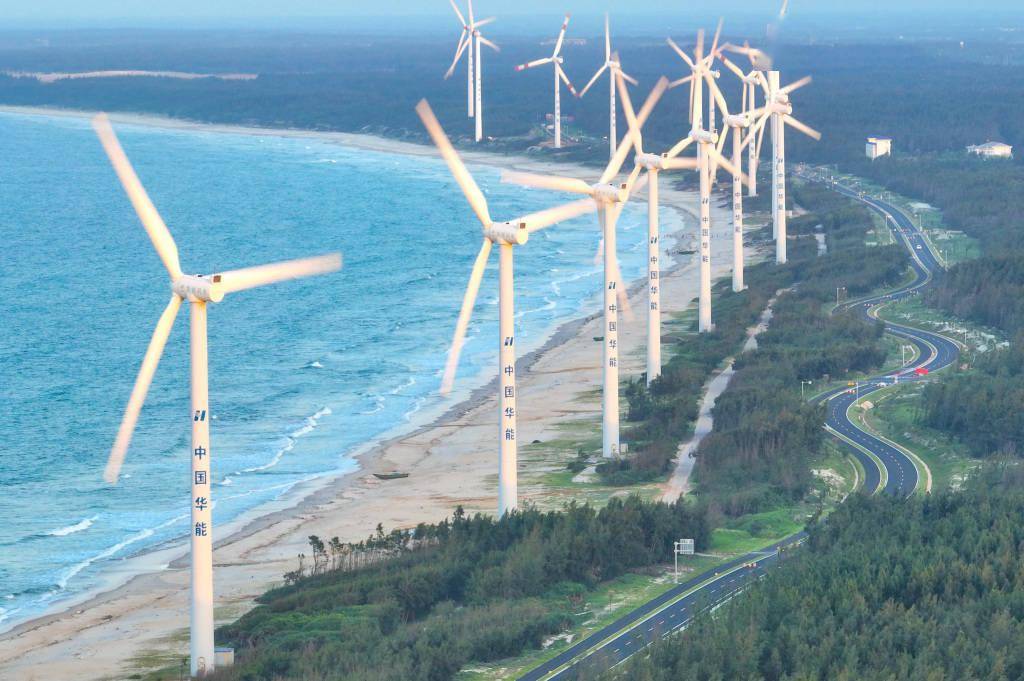 海边矗立一排风力发电机,它们高大的身影在阳光下显得格外醒目.