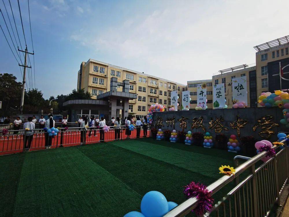 在涿州市双塔中学的校门口,写有"我们开学啦"字样的展板被五颜六色的