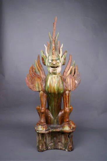 头生长角,脑后生戟,肩生双翼,张口怒目,面目狰狞,蹲坐于不规则墩形