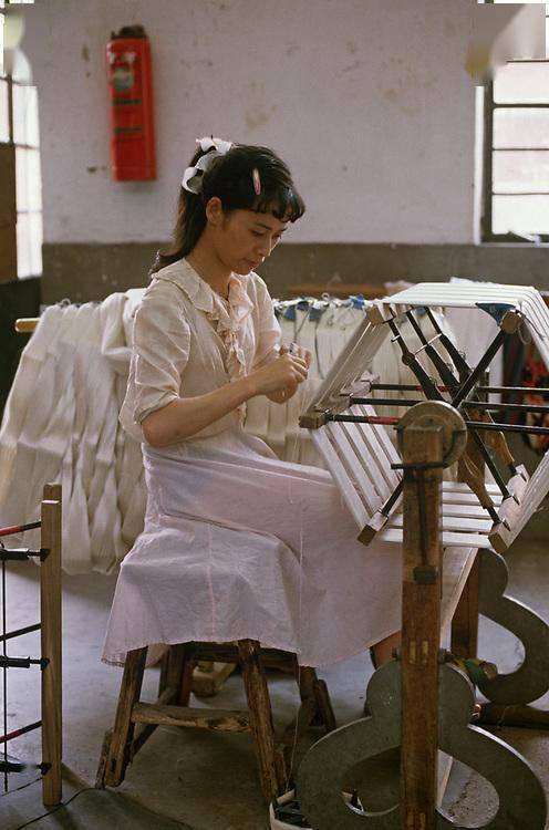 6,一位打扮时髦的女工,她坐在椅子上,用脚踩着踏轮,带动了上方的卷轮